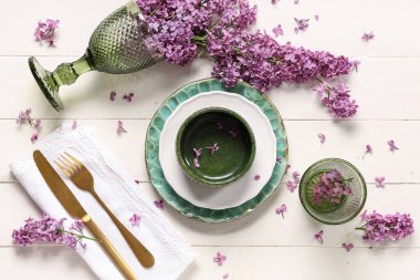 Beyaz ahşap arka planda leylak çiçekleri olan güzel bir masa.