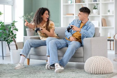 Happy young couple playing video games on sofa at home
