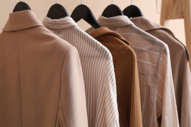 Bej arka planda askıda asılı kadın giysileri