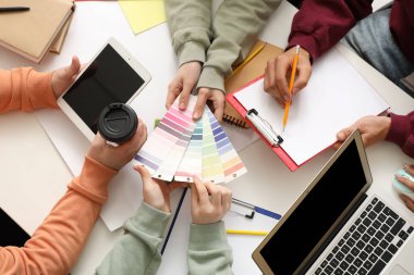 Beyaz masadaki boya renk paletleri ile çalışan iş adamları, üst görünüm