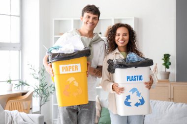 Evlerinde çöp konteynırları olan genç bir çift. Geri dönüşüm kavramı