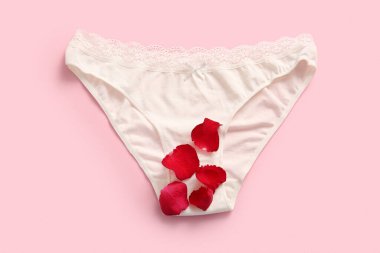 Pembe arka planda gül yaprakları olan adet külotu.