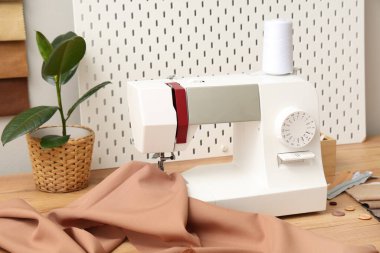 Ahşap masa üzerinde terzi malzemeleri olan modern dikiş makinesi.