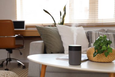 Oturma odasındaki masa üzerinde bitki ve şarjörlü hava nemlendirici.