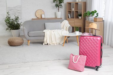 Şapka, plaj çantası ve terliklerle dolu bavul oturma odasının içinde.