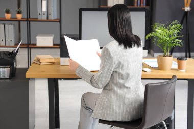 İş yerinde modern bilgisayarla çalışan genç bir kadın şık bir ofiste çalışıyor.