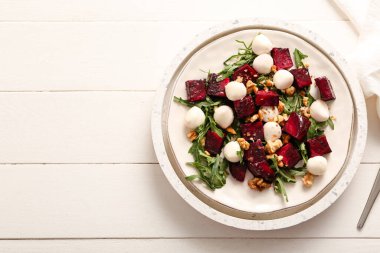 Beyaz ahşap arka planda pancar ve mozzarella peynirli taze salata.