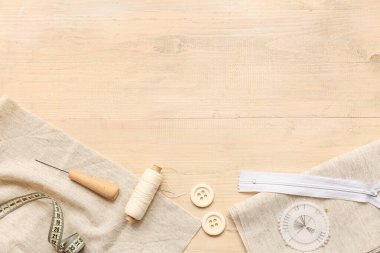 Fermuarlı kompozisyon ve tahta bej arka planda dikiş aksesuarları. Üst görünüm