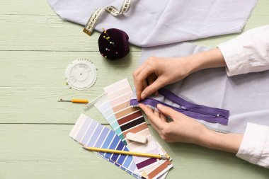 Yeşil arka planda dikiş malzemeleri olan kadın terzinin elleri. Üst görünüm