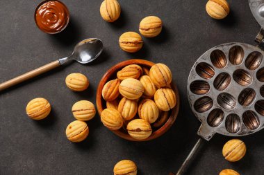 Lezzetli ceviz şekilli kurabiyeler, kaynamış süt ve siyah grunge masasında pişirme formu.