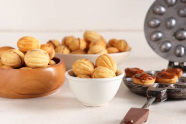 Lezzetli ceviz şekilli kurabiyeler, kaynamış süt ve beyaz ahşap masada pişirme biçimi.