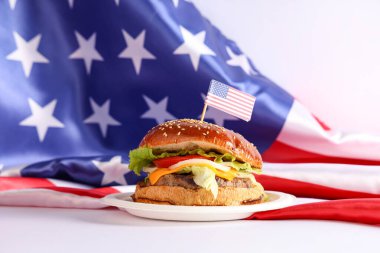 Beyaz arka planda ABD bayrakları olan lezzetli bir burger. Amerikan Bağımsızlık Günü kutlamaları