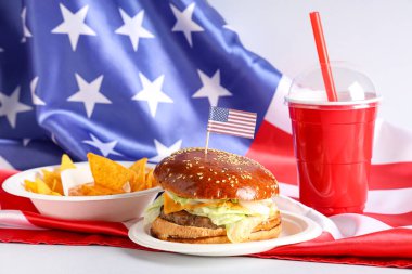 Nachos, kola ve beyaz arka planda Amerikan bayrakları olan lezzetli bir burger. Amerikan Bağımsızlık Günü kutlamaları