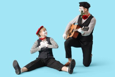 Mavi arka planda gitarı olan birkaç pandomist.