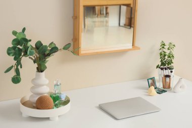 Giyinme odasındaki masada dizüstü bilgisayarı olan makyaj malzemeleri.