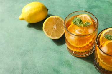 Yeşil grunge arka planda lezzetli soğuk buzlu çay ve limonlar, yakın plan.