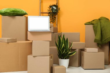 Odada turuncu duvarın yanındaki kutuları taşıyan boş bir dizüstü bilgisayar.