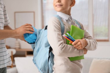 Küçük çocuk ve babası okul çantalarını sırt çantasına koyuyorlar.