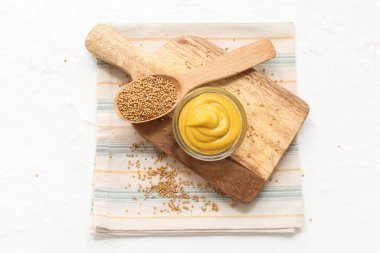 Kremalı hardal ve beyaz arka planda tohumları olan kaşık.