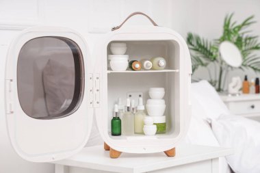 Evdeki masada şişelerle ve kozmetik ürünlerle dolu küçük bir buzdolabı.