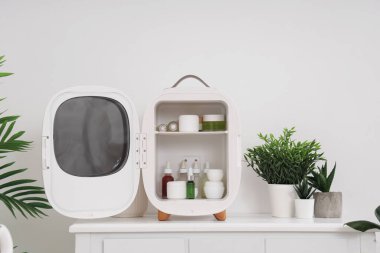 Evde kozmetik ürünleri olan küçük bir buzdolabı.