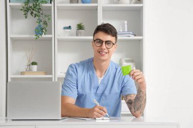 Genç doktor klinikte prezervatif gösteriyor.