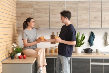 Mutlu genç çift mutfakta taze meyve suyu içiyor.