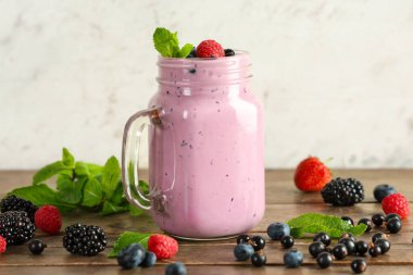 Farklı böğürtlenli ve ahşap masada naneli Mason kavanozu.