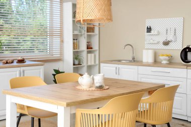 Yemek masası, beyaz tezgah ve çivi tahtası olan şık bir mutfak.