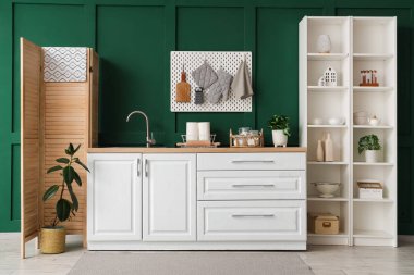 Beyaz tezgahlı, yeşil duvarlı, şık bir mutfak.