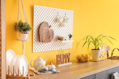 Siyah tezgahları ve sarı duvarın yanındaki tahta tahtaları olan şık bir mutfak.