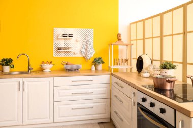 Beyaz tezgahlı, sarı duvarlı, şık bir mutfak.