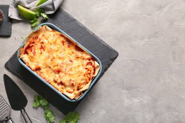 Lezzetli enchilada, baharatlar ve grunge arkaplanda mutfak gereçleri ile pişirme yemeği.