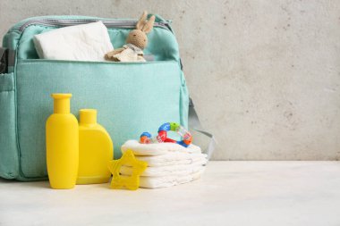 Gri arka planda masasında krema şişeleri olan bebek çantası