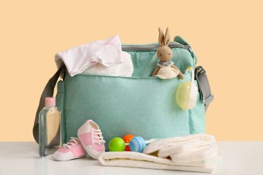 Bej arka planda tavşanlı oyuncaklı bebek çantası