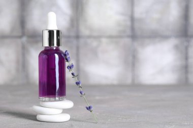 Spa taşları, bir şişe lavanta esaslı yağ ve arkaplanda çiçekler.