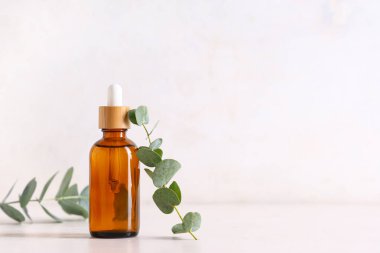 Işık arka planında bir şişe okaliptüs yağı, yakın plan.