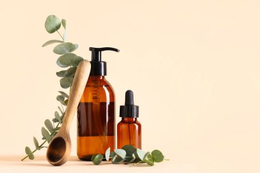 Ahşap kaşık ve bej arka planda gerekli okaliptüs şişeleri.