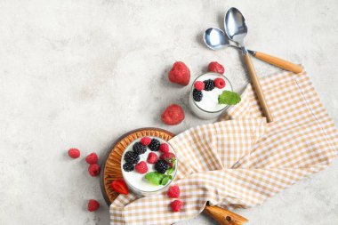 Beyaz arka planda taze ahududu ve böğürtlenli lezzetli yoğurt bardakları