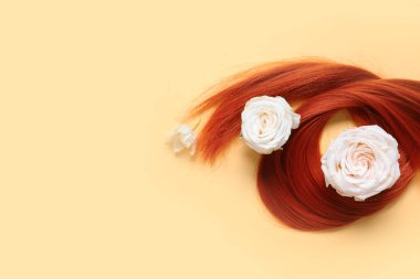 Kızıl saç teli ve soluk sarı arka planda çiçekler, yakın plan.