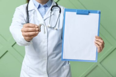 İşitme cihazı ve renk duvarının yanında boş panosu olan kadın doktor.