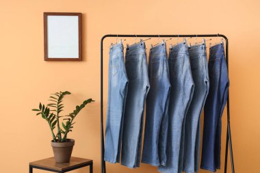 Odada bej duvarın yanında kot pantolon var.