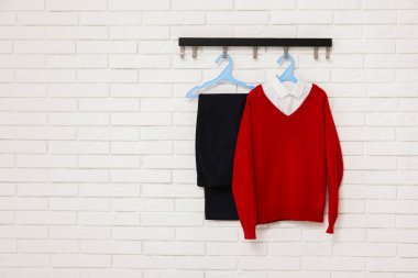 Açık tuğla duvarda asılı şık okul üniforması