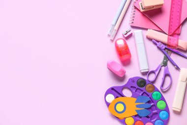 Pembe arka planda farklı okul kırtasiyesine sahip kağıt roket.