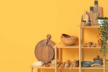 Mutfakta sarı duvarın yanında bulaşık takımı olan modern raf ünitesi.