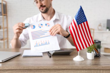 Ofiste çalışan, evrakları ve bayrağı olan yakışıklı genç adam, yakın plan.