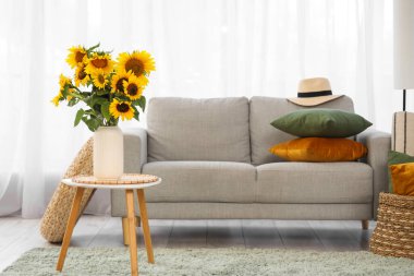 Masasında vazo ve kanepe olan aydınlık oturma odasının içinde.