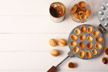 Lezzetli ceviz şekilli kurabiyeler ve beyaz ahşap arka planda kaynamış konserve süt.