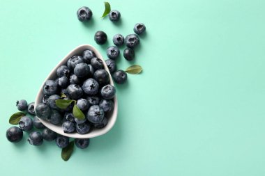 Turkuaz arka planda olgun yaban mersinli kase