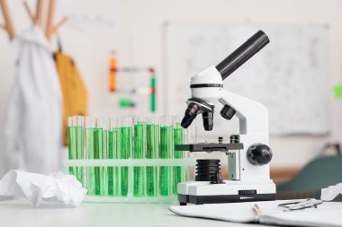 Modern mikroskop, kimyasal mataralar ve genç kızların odasındaki masada duran defter.